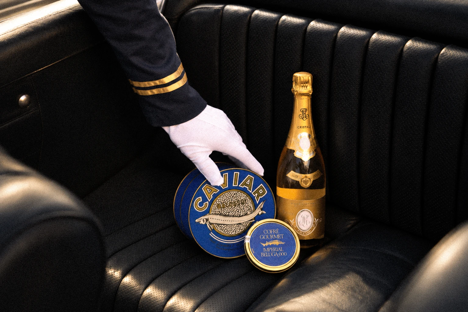 Latas de caviar Cofré y champagne presentadas con guante blanco